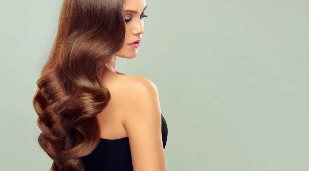 wanita dengan rambut sehat memberikan contoh cara merawat rambut agar sehat dan tebal dengan rangkaian perawatan Kérastase