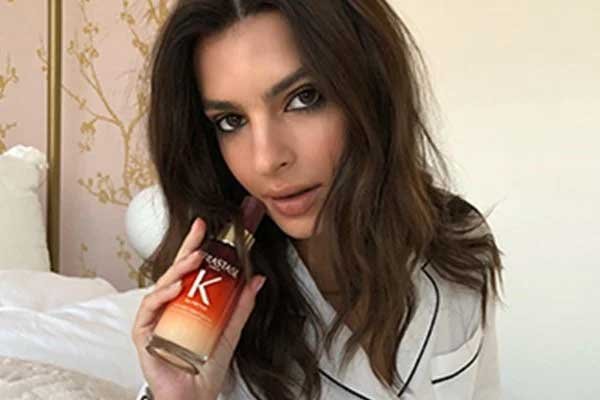 Emily Ratajkowski memegang Kérastase Nutritive 8H Magic Night Serum, salah satu serum rambut yang bagus