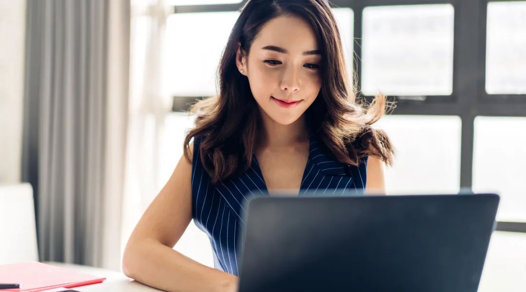 seorang wanita sedang bekerja di depan laptop dengan styling rambut wanita karir