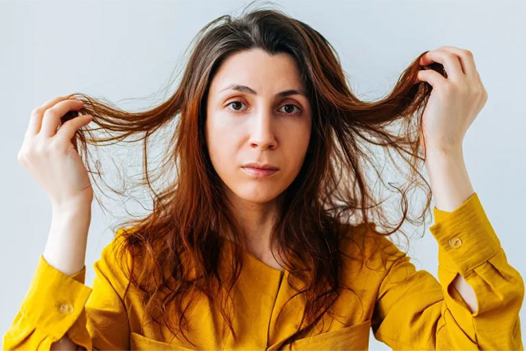 wanita memegang rambut lepek dan mencari cara agar rambut bervolume