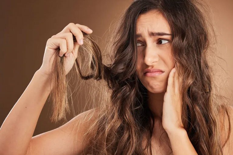 wanita memegang rambut kering miliknya